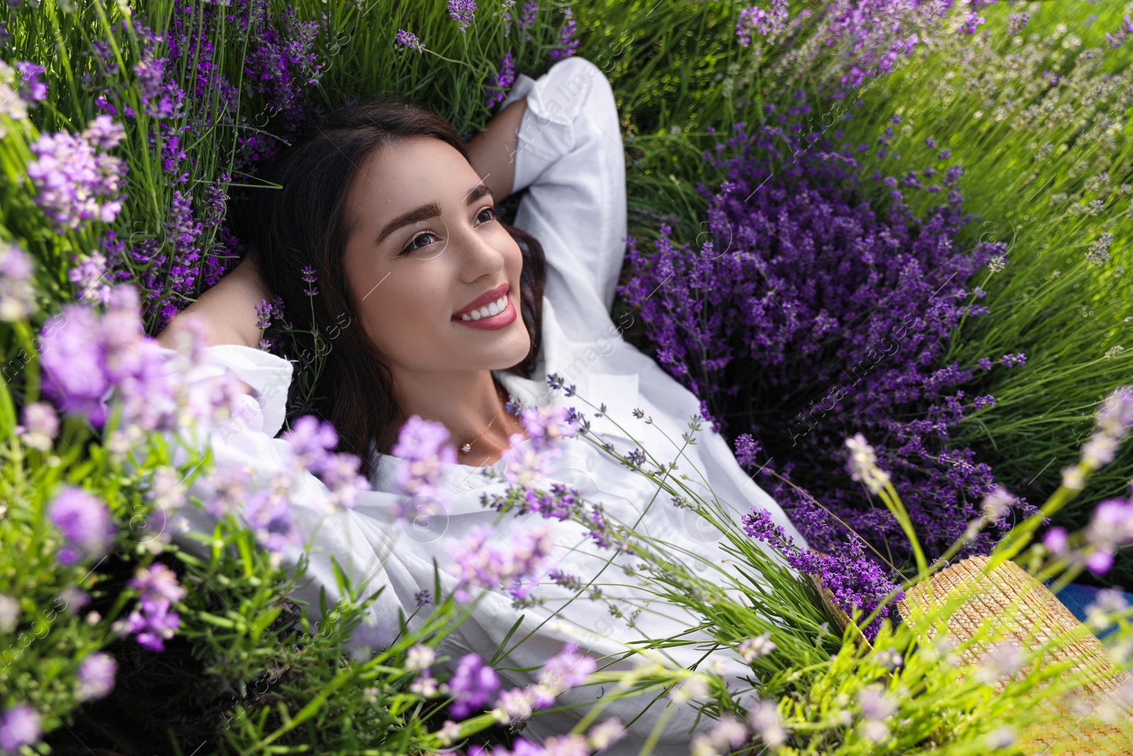 Photo of Young woman lying in lavender field on summer day