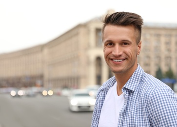 Portrait of handsome young man on city street. Space for text