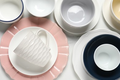 Beautiful ceramic dishware and cup on white table, flat lay