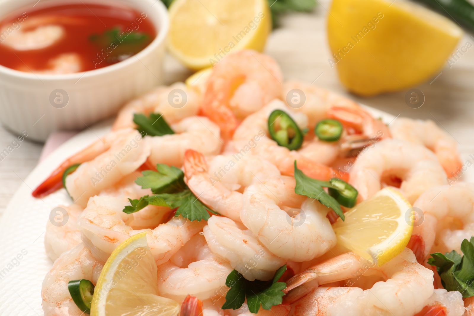 Photo of Tasty boiled shrimps with cocktail sauce, chili and parsley on table, closeup