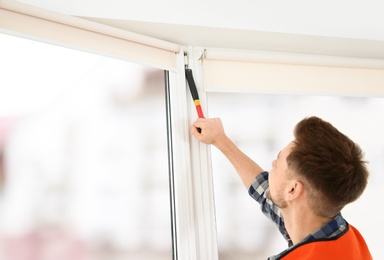 Construction worker installing plastic window in house