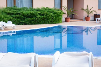 Photo of Many sunbeds near outdoor swimming pool at resort