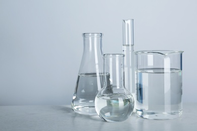 Photo of Laboratory glassware with liquid on table against gray background. Chemical analysis