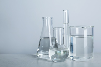 Laboratory glassware with liquid on table against gray background. Chemical analysis