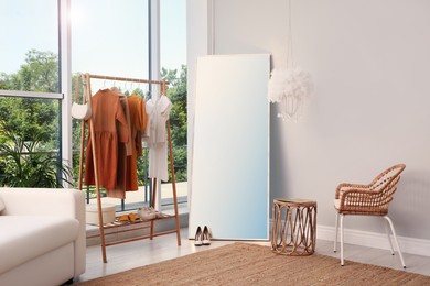 Photo of Dressing room interior with clothing rack and comfortable furniture