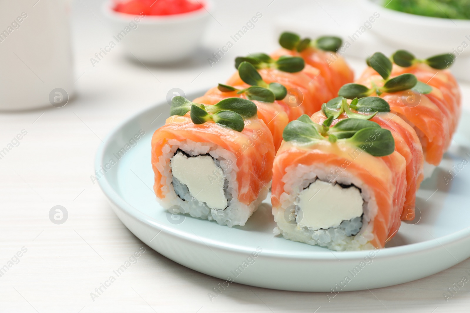 Photo of Tasty sushi rolls with salmon served on white table, closeup
