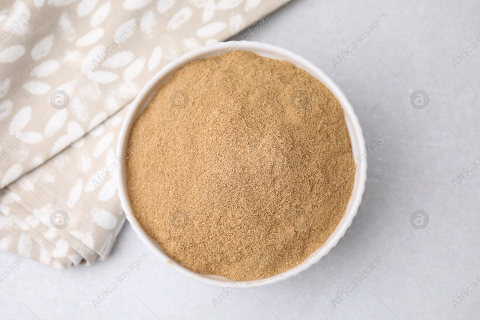 Photo of Dietary fiber. Psyllium husk powder in bowl on light grey table, top view