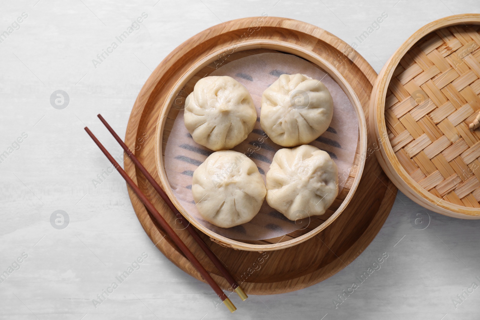 Photo of Delicious bao buns (baozi) and chopsticks on light table, top view