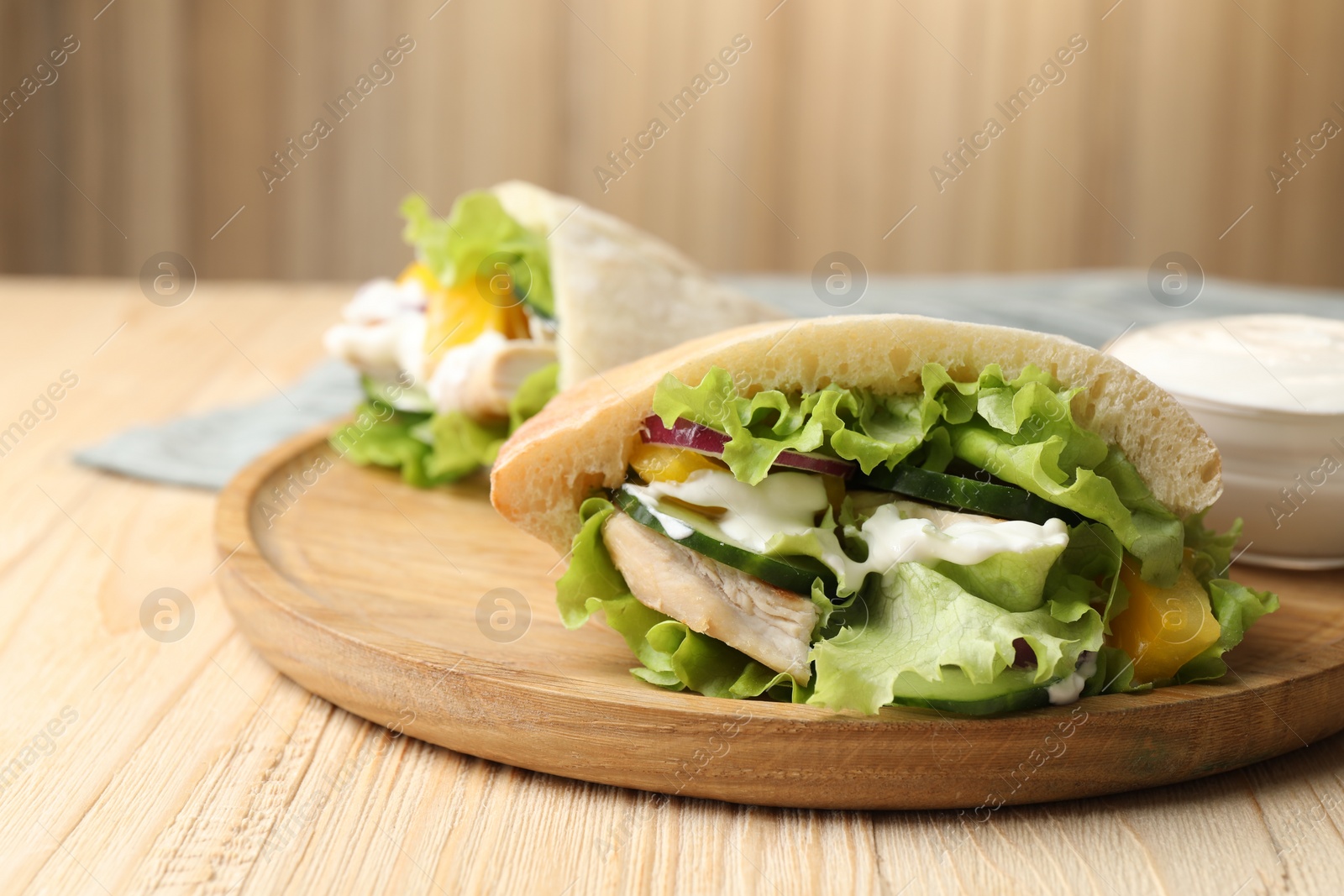 Photo of Delicious pita sandwiches with chicken breast and vegetables on wooden table, closeup