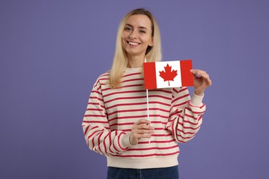 Image of Happy young woman with flag of Canada on purple background