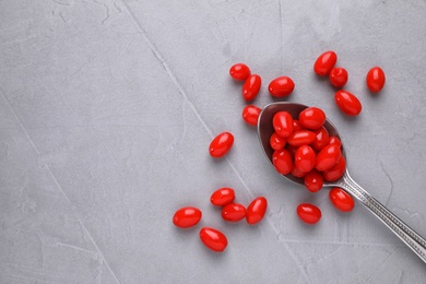 Photo of Spoon with fresh goji berries on grey background, flat lay. Space for text