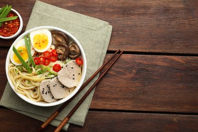 Photo of Delicious ramen with meat in bowl served on wooden table, flat lay. Space for text. Noodle soup