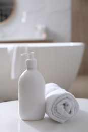 Photo of Bottle of shower gel and fresh towel on white table in bathroom