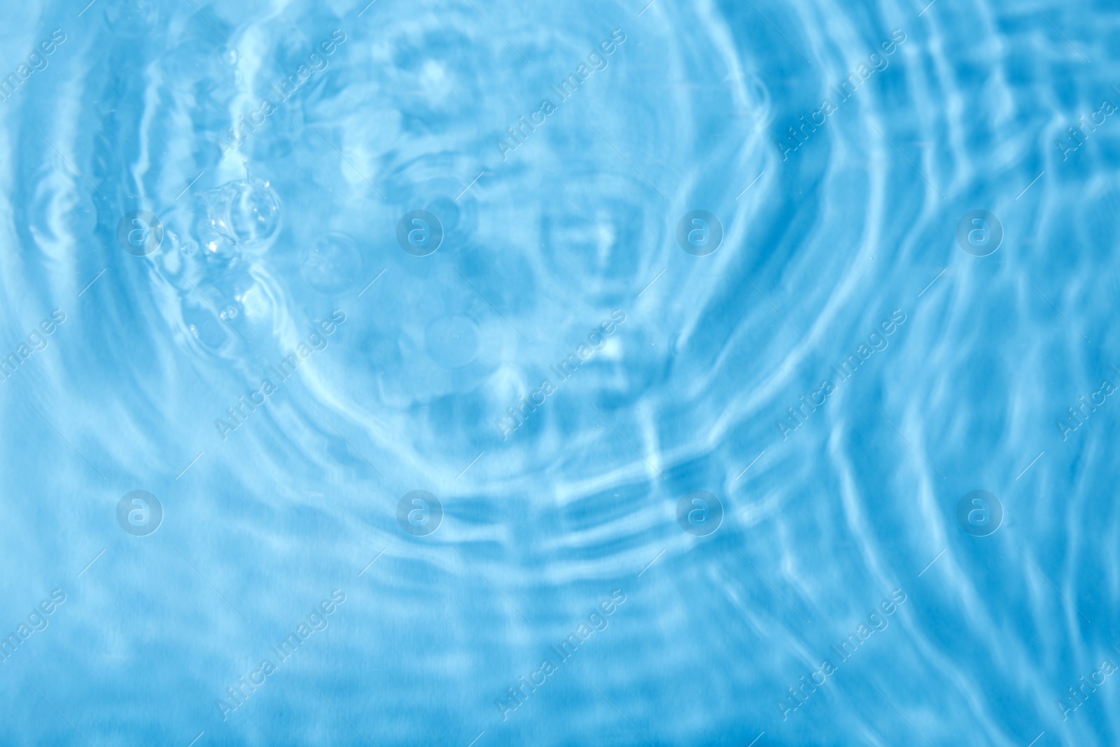 Photo of Concentric waves on blue water surface after falling drops, top view
