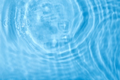 Photo of Concentric waves on blue water surface after falling drops, top view