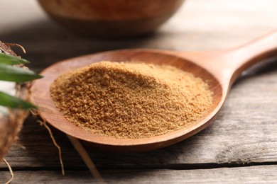 Photo of Spoon with coconut sugar on wooden table, closeup