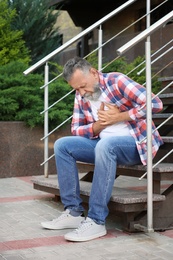 Mature man having heart attack on stairs, outdoors