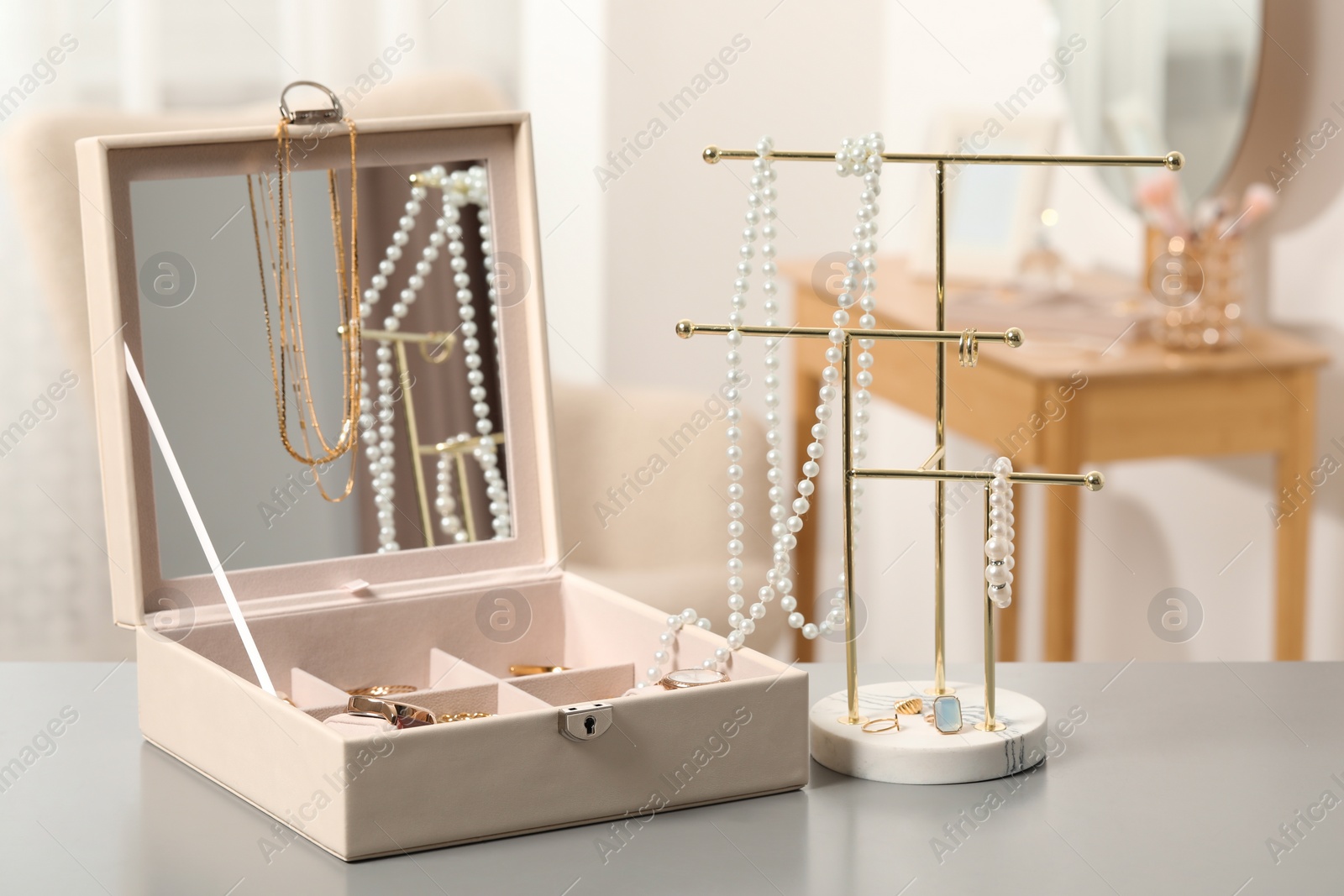 Photo of Jewelry box with many different accessories and stand on light grey table indoors