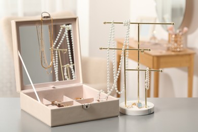 Jewelry box with many different accessories and stand on light grey table indoors