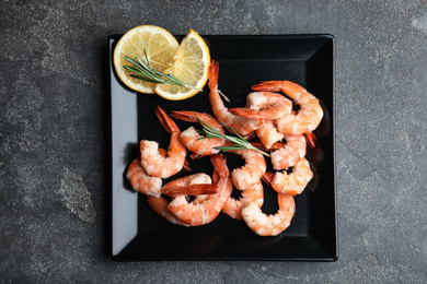 Delicious cooked shrimps with rosemary and lemon on grey table, top view