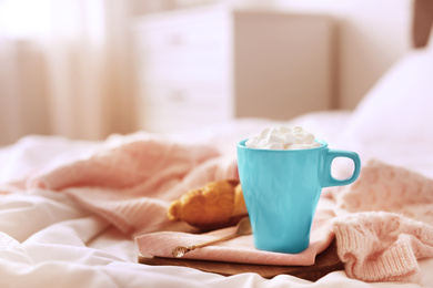 Photo of Morning coffee with marshmallow and croissant on bed indoors. Space for text