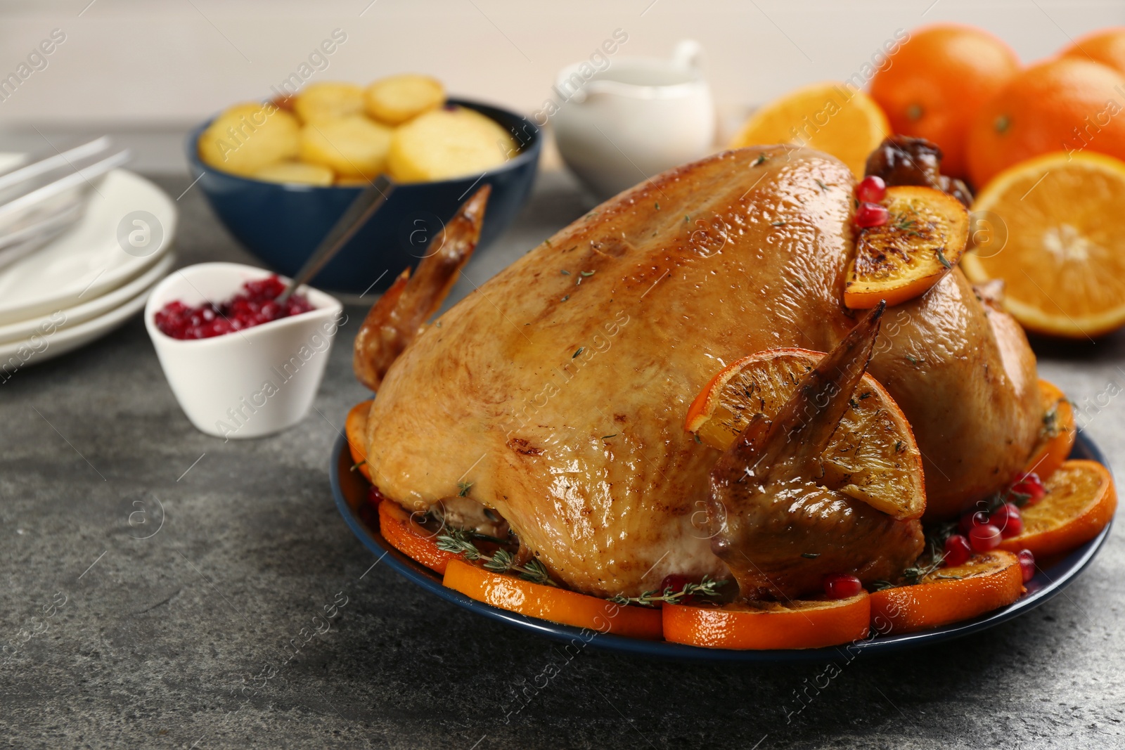 Photo of Delicious chicken with oranges and pomegranate on grey table