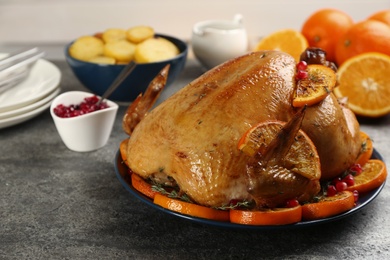 Photo of Delicious chicken with oranges and pomegranate on grey table