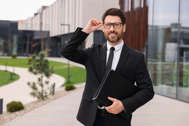 Photo of Real estate agent with leather portfolio outdoors. Space for text