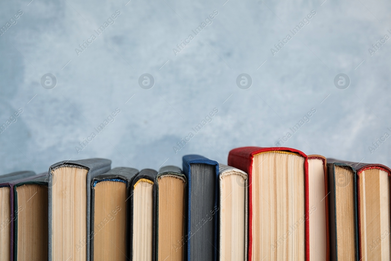 Photo of Stack of hardcover books on light blue background. Space for text