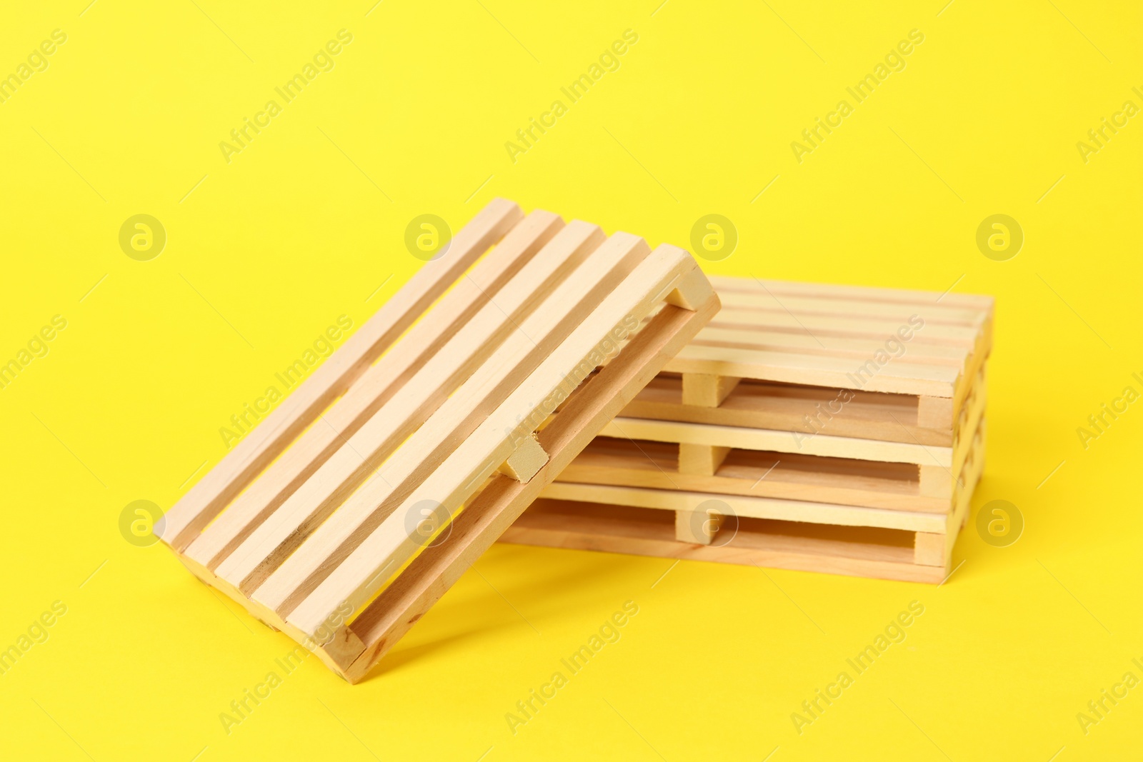 Photo of Many small wooden pallets on yellow background