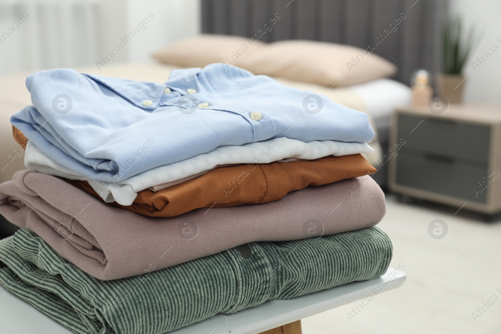 Photo of Stack of different folded clothes white on table, closeup