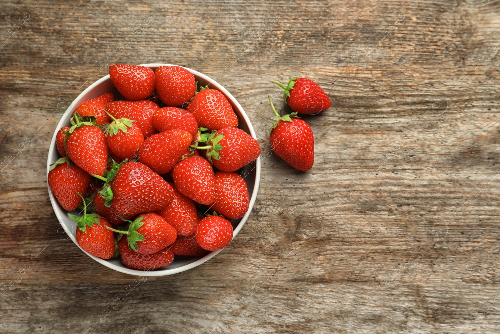 Photo of Bowl with fresh ripe strawberries on wooden background, top view