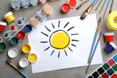 Photo of Flat lay composition with child's painting of sun on grey table