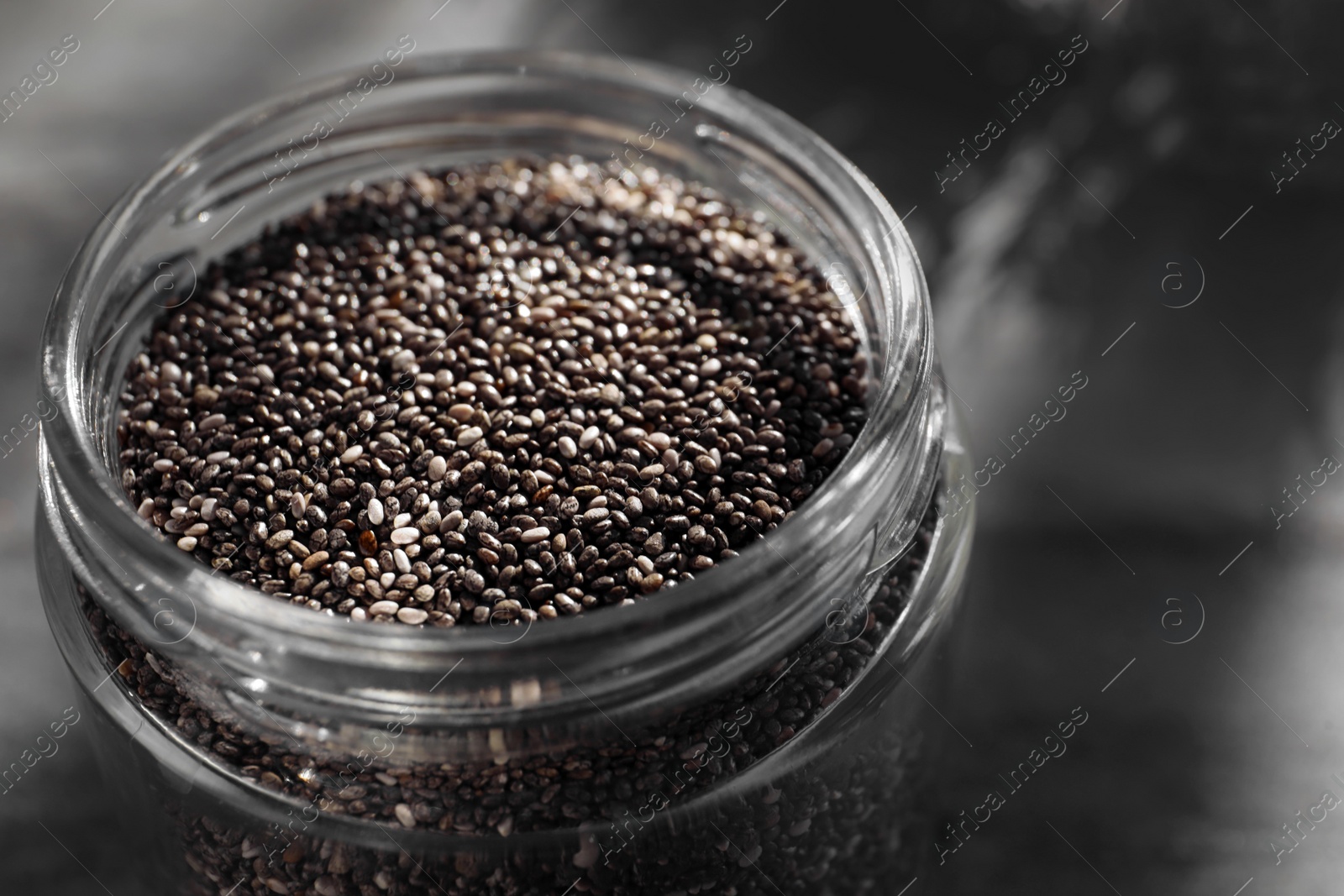 Photo of Glass jar with chia seeds on table, closeup
