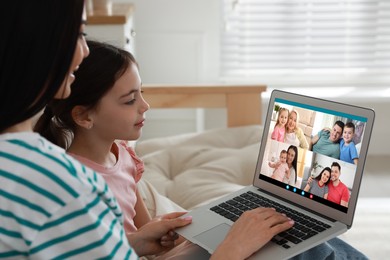 Image of Mother and daughter having online meeting with family members via videocall application at home