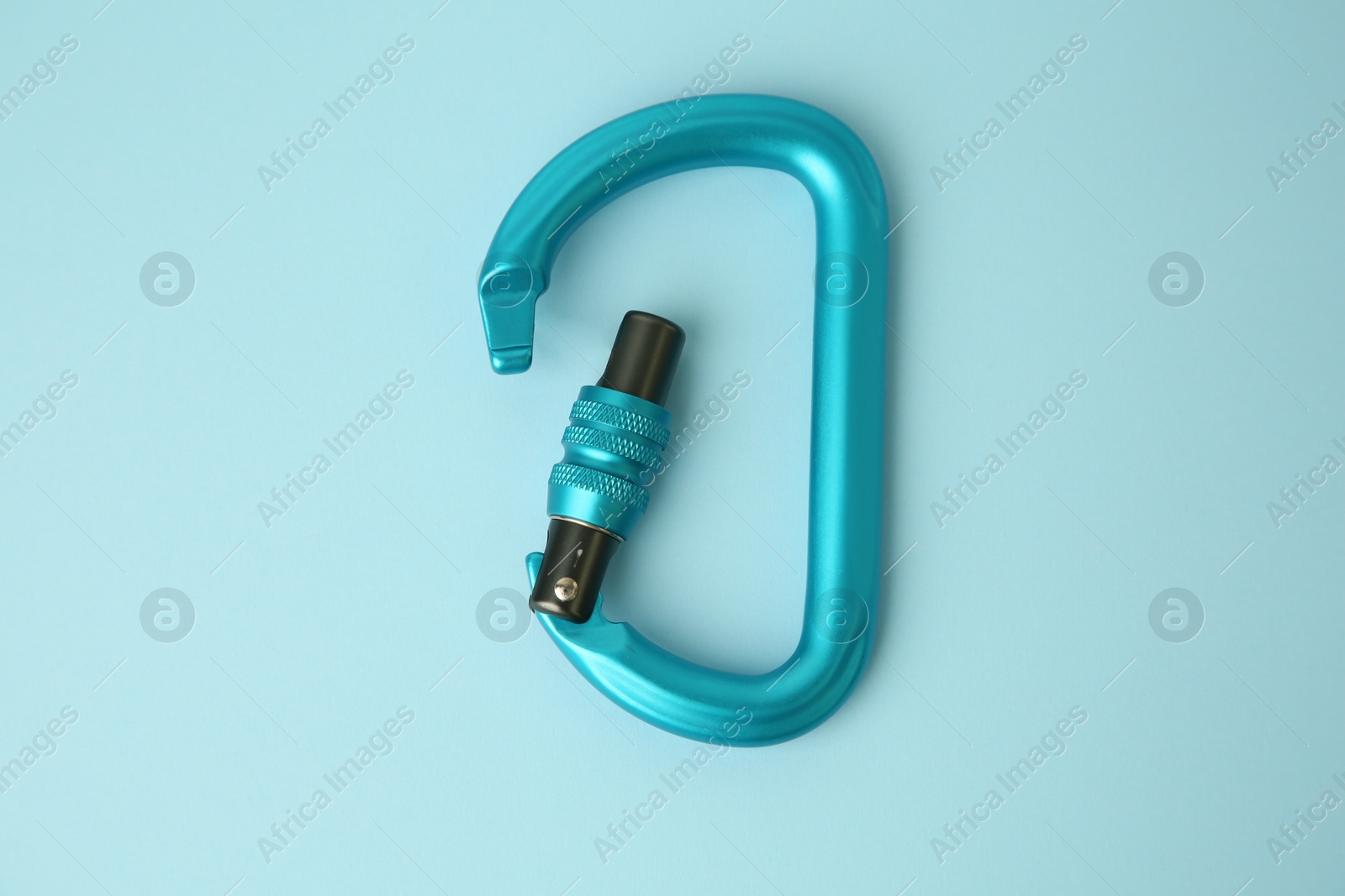 Photo of One carabiner on light blue background, top view