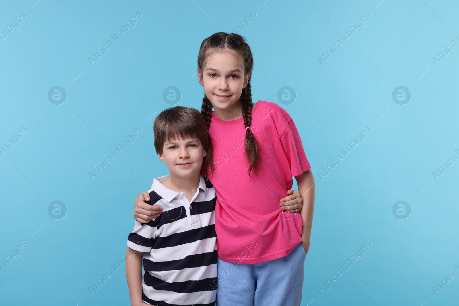 Photo of Happy brother and sister hugging on light blue background