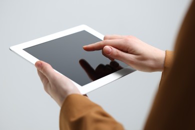 Photo of Closeup view of woman using modern tablet on light grey background