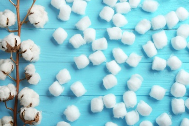 Flat lay composition with cotton balls and flowers on blue wooden background