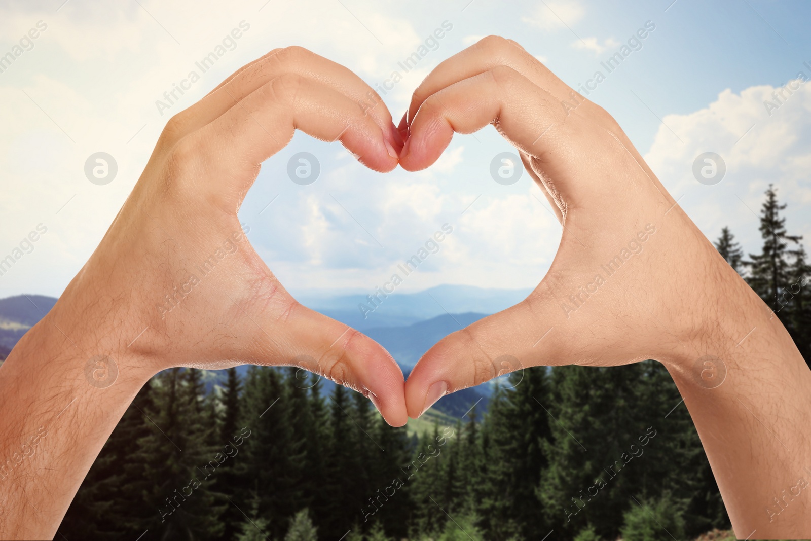 Image of Man making heart with hands in mountains on sunny day, closeup