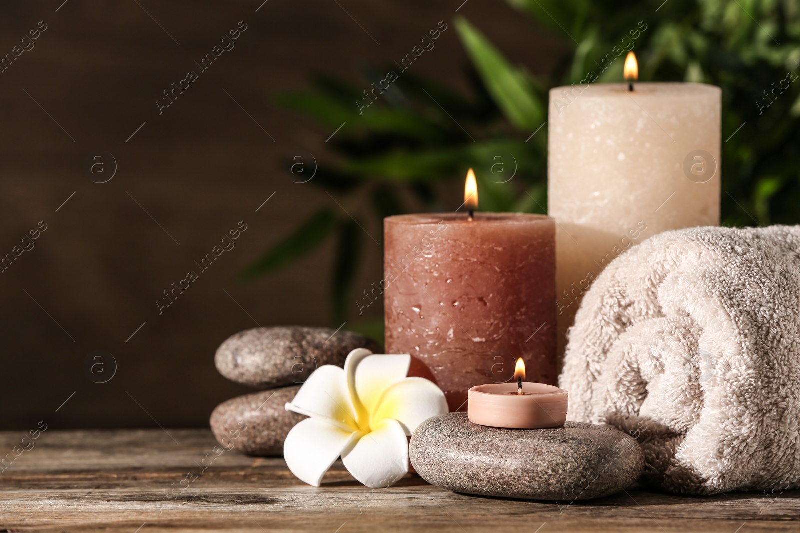 Photo of Composition with candles and spa stones on wooden table. Space for text