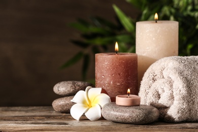 Photo of Composition with candles and spa stones on wooden table. Space for text