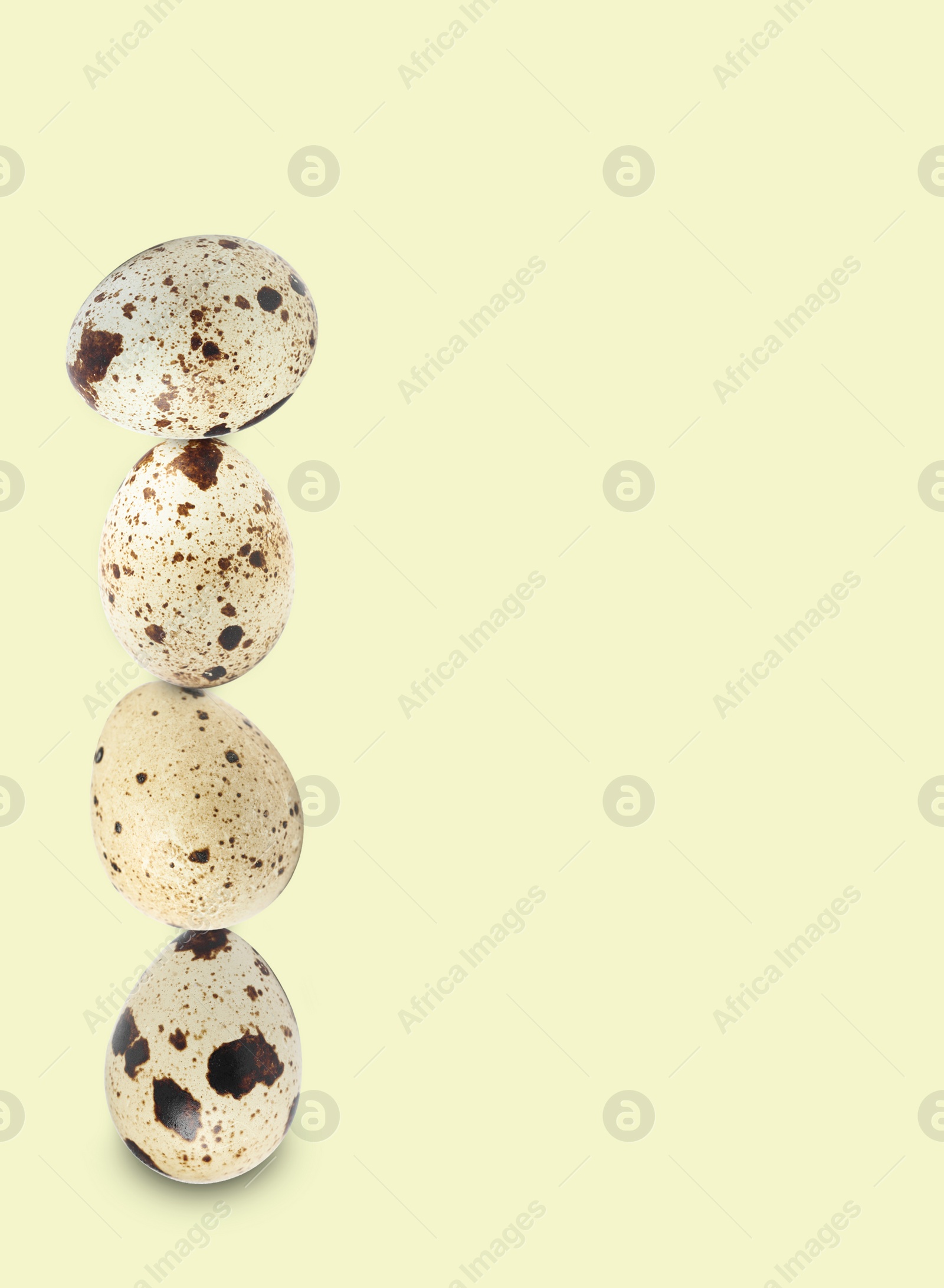 Image of Stacked speckled quail eggs on light beige background. Space for text