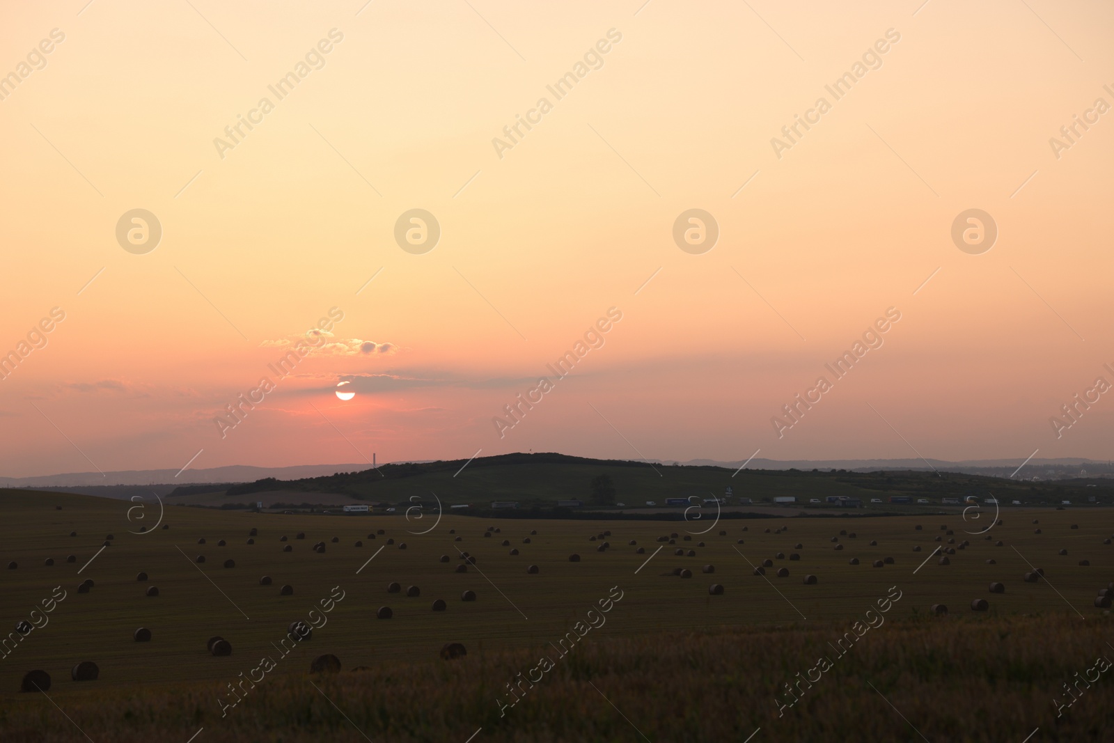 Photo of Beautiful view of agricultural field with hay bales at sunset