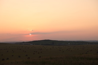 Photo of Beautiful view of agricultural field with hay bales at sunset