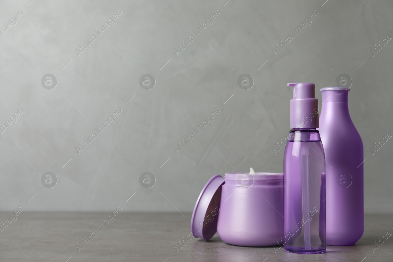 Photo of Different hair products on grey table. Space for text