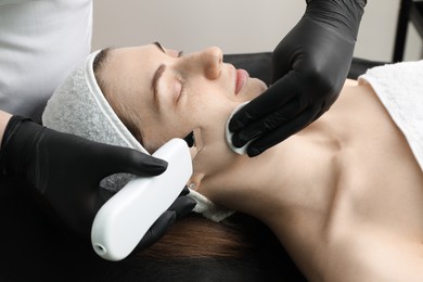 Cosmetologist using ultrasonic scrubber, closeup. Client having cleansing procedure indoors