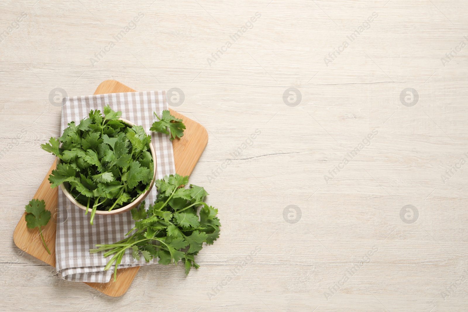 Photo of Bunch of fresh aromatic cilantro on white wooden table, top view. Space for text