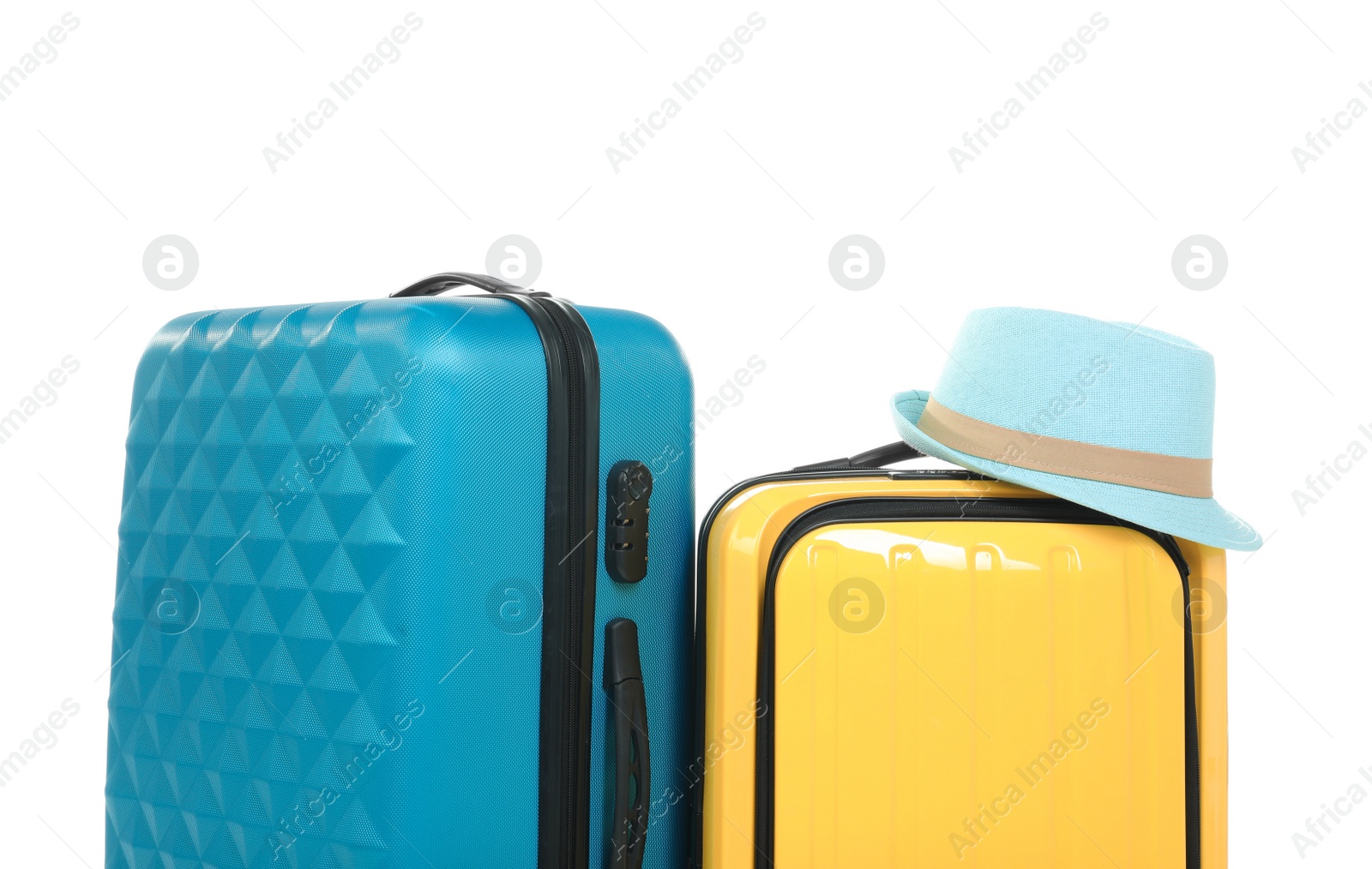 Photo of New suitcases and hat packed for journey on white background