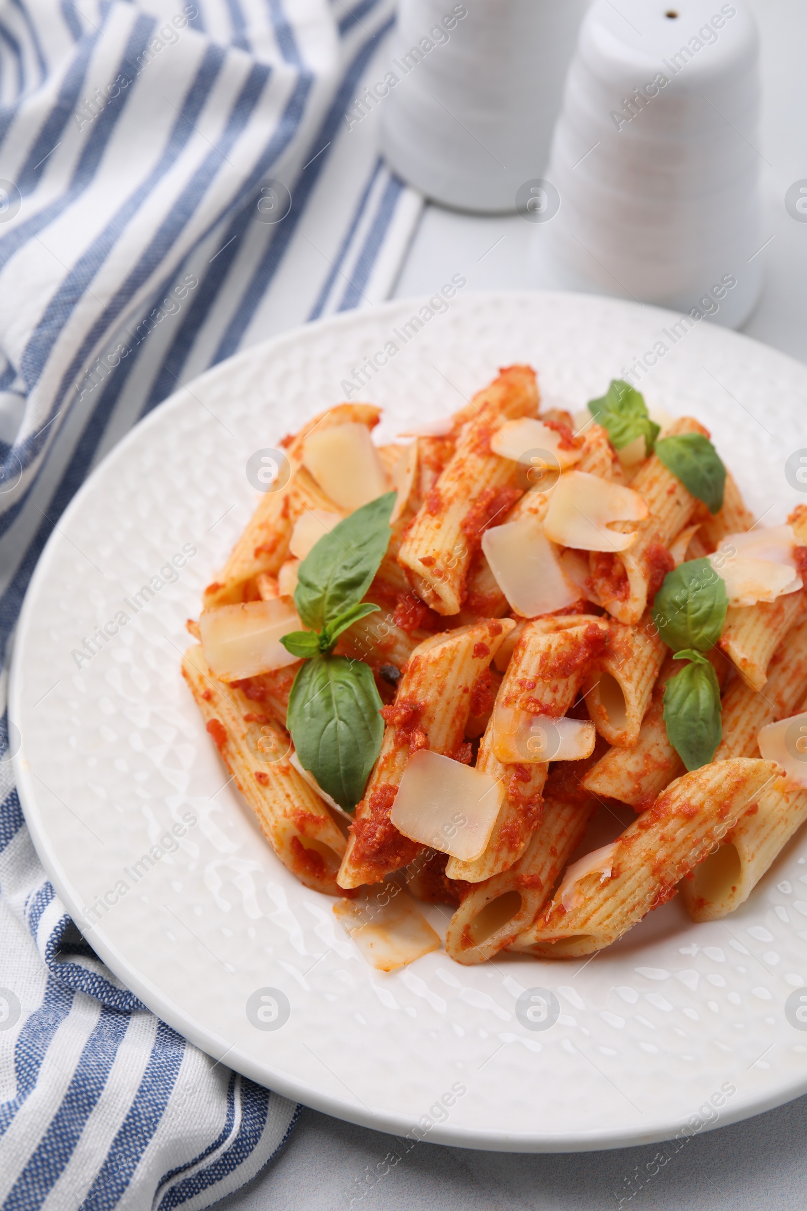 Photo of Tasty pasta with tomato sauce, cheese and basil on table